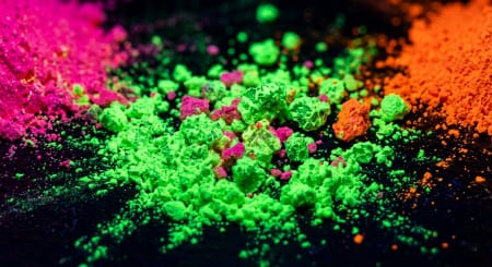 macro view of UV fluorescent pigment particles glowing under ultraviolet light