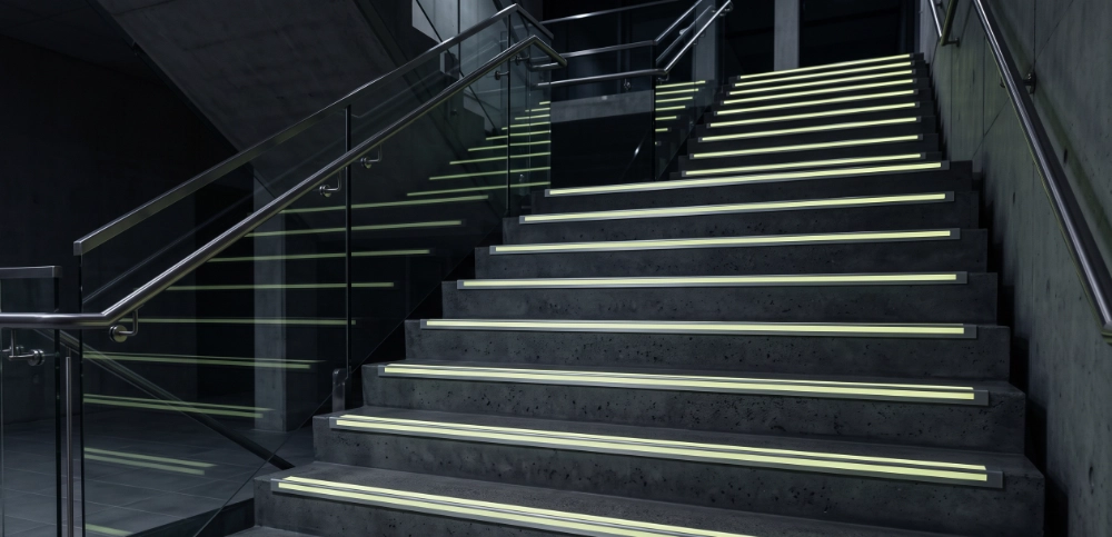 Photorealistic modern commercial staircase with aluminium L-shaped photoluminescent stair nosings fitted precisely along the leading edge of every step